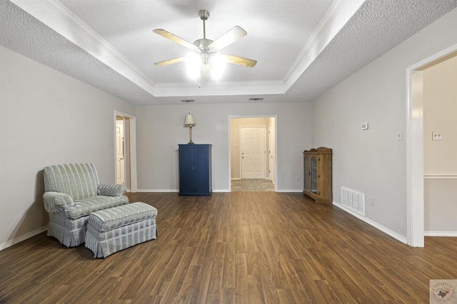 sitting room with a textured ceiling, a tray ceiling, and crown molding