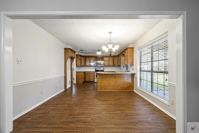 kitchen with appliances with stainless steel finishes, decorative light fixtures, sink, kitchen peninsula, and a notable chandelier