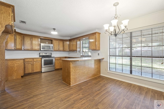 kitchen with stainless steel appliances, hanging light fixtures, kitchen peninsula, and dark hardwood / wood-style flooring