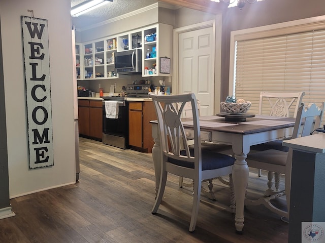 kitchen featuring wood-type flooring, a textured ceiling, appliances with stainless steel finishes, and ornamental molding