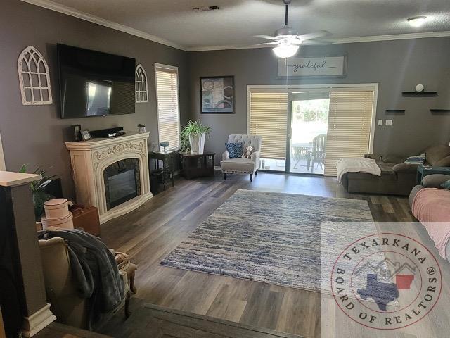 living room with ceiling fan, ornamental molding, and dark hardwood / wood-style flooring