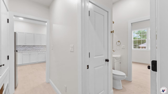corridor with light wood-style flooring and baseboards