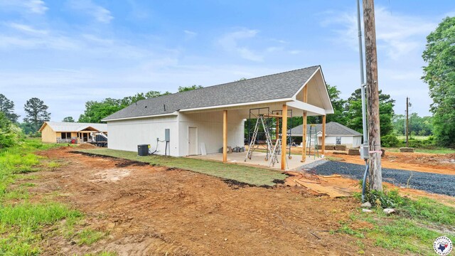 exterior space with roof with shingles and a patio