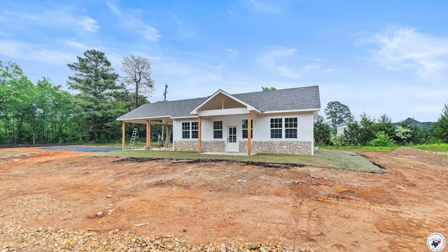 view of front of property with roof with shingles and stone siding
