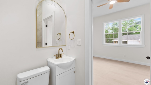 bathroom with toilet, baseboards, a ceiling fan, wood finished floors, and vanity