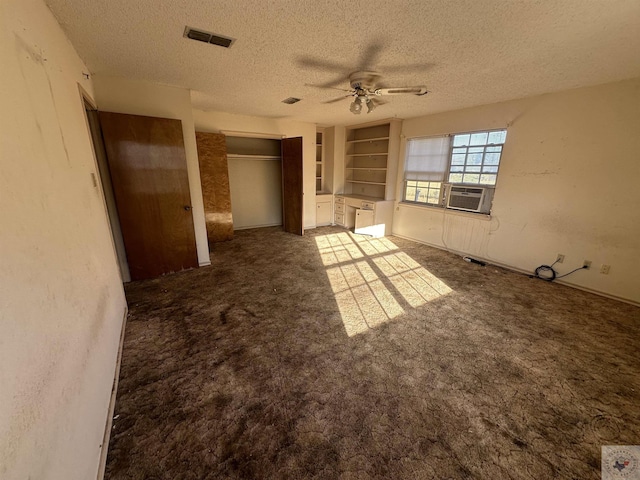 interior space featuring ceiling fan, a textured ceiling, built in features, and cooling unit