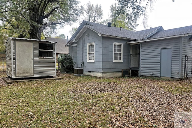 back of property with a lawn, cooling unit, and a storage unit