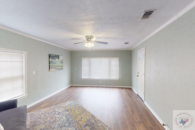 unfurnished room featuring dark wood-type flooring, a textured ceiling, crown molding, and a healthy amount of sunlight