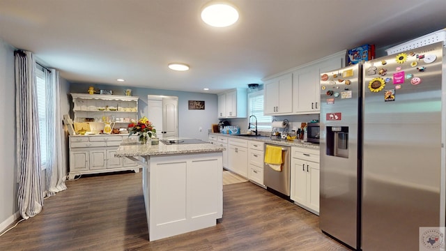 kitchen featuring light stone counters, white cabinetry, appliances with stainless steel finishes, and a center island