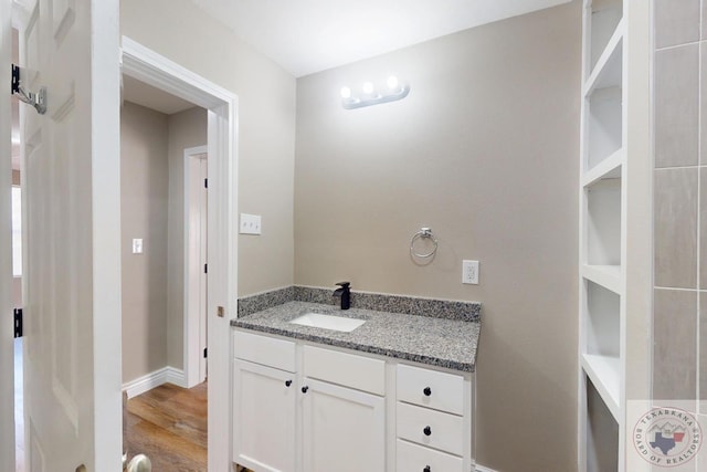 bathroom featuring baseboards, wood finished floors, and vanity