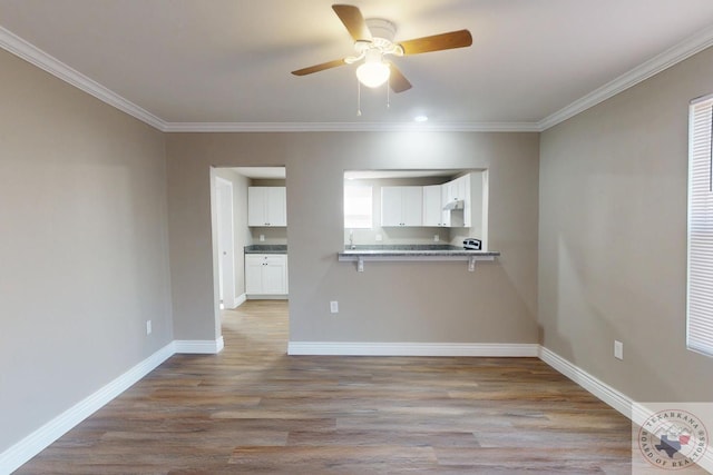 interior space with light wood-style flooring, ceiling fan, baseboards, and ornamental molding