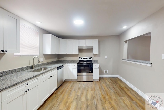 kitchen featuring under cabinet range hood, light stone counters, stainless steel appliances, white cabinetry, and a sink