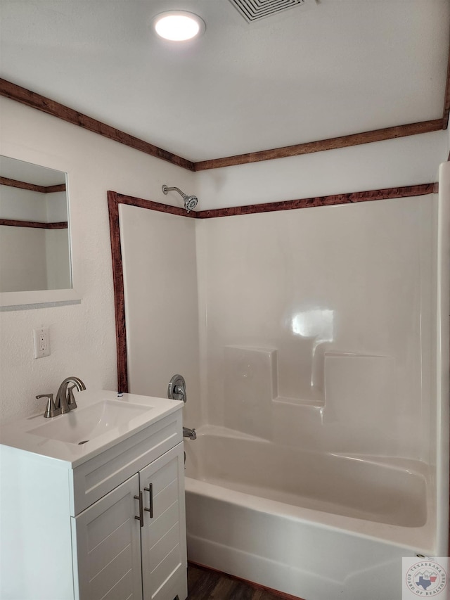 bathroom with hardwood / wood-style flooring, vanity, and shower / washtub combination