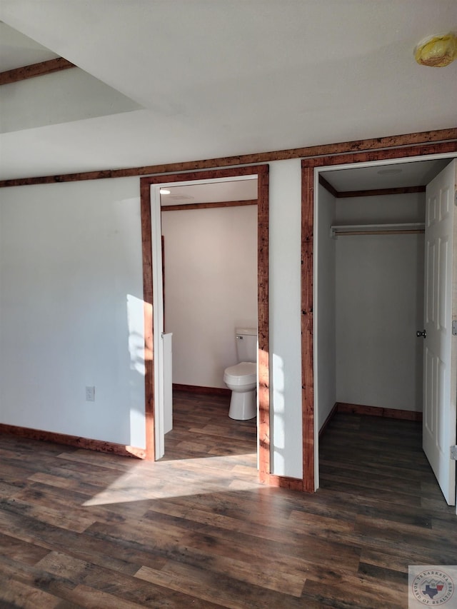 unfurnished bedroom with dark wood-type flooring, connected bathroom, and a closet