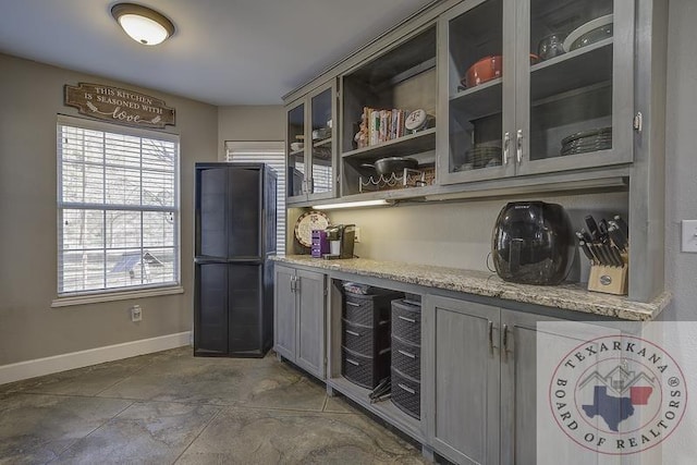 kitchen featuring light stone counters and gray cabinetry