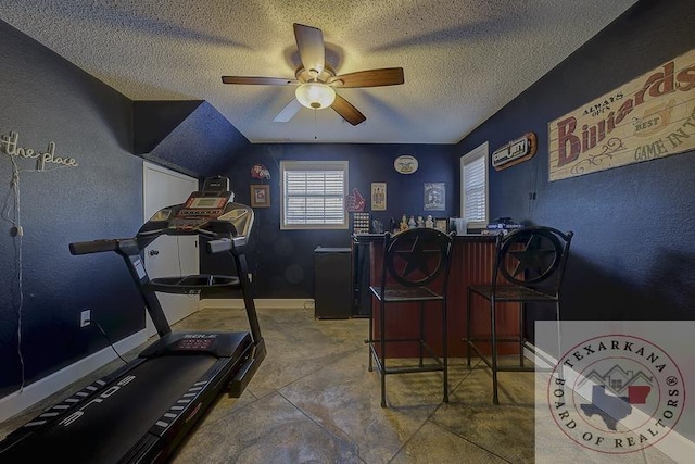 workout room featuring ceiling fan, bar area, vaulted ceiling, and a textured ceiling