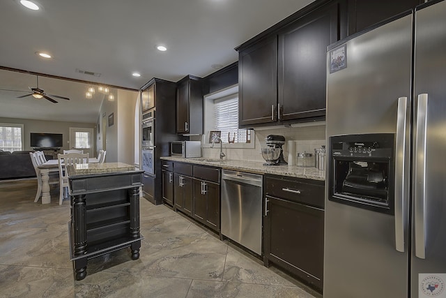 kitchen with ceiling fan, tasteful backsplash, stainless steel appliances, light stone counters, and dark brown cabinetry