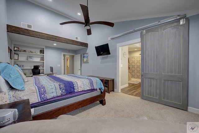 carpeted bedroom featuring ceiling fan, ensuite bathroom, a barn door, and vaulted ceiling