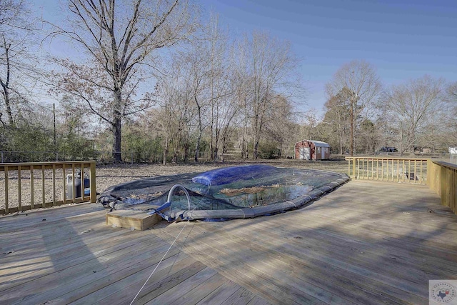 view of swimming pool featuring a wooden deck and a storage shed