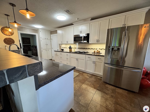 3905 Colorado St, Texarkana, TX 75503 - kitchen featuring stainless steel appliances, dark countertops, a sink, white cabinets, and hanging light fixtures