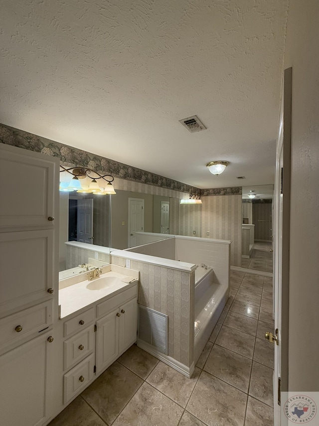 bathroom with vanity, a bath, tile patterned floors, and a textured ceiling