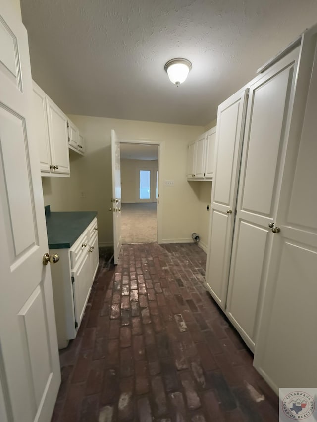 clothes washing area featuring hookup for an electric dryer, cabinets, and a textured ceiling