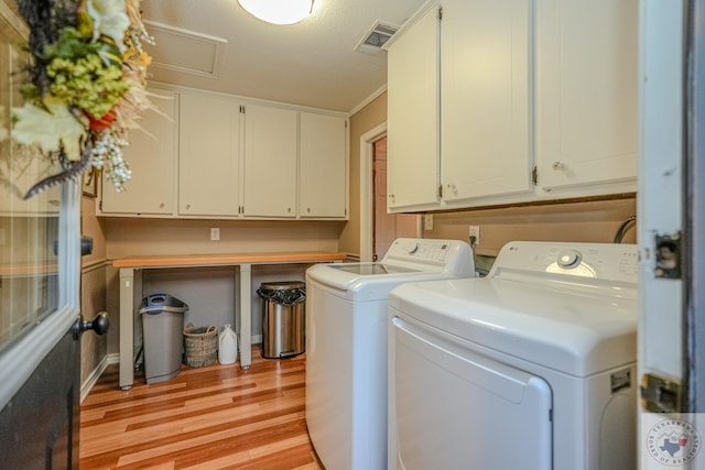 laundry room with a textured ceiling, light hardwood / wood-style floors, cabinets, and washer and dryer