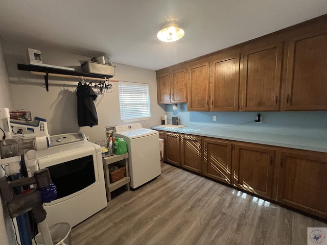 laundry room featuring light hardwood / wood-style floors, cabinets, and washing machine and clothes dryer