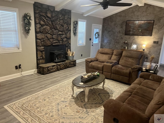 living room with hardwood / wood-style floors, a wood stove, ceiling fan, a healthy amount of sunlight, and lofted ceiling with beams