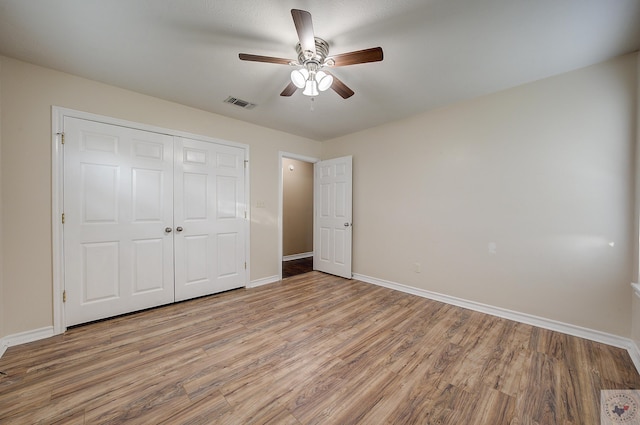 unfurnished bedroom featuring ceiling fan, a closet, and light wood-type flooring