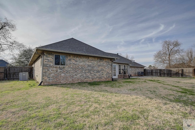 back of property featuring a lawn and central air condition unit