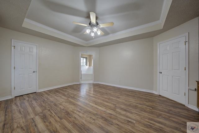 unfurnished room with a raised ceiling, ornamental molding, and hardwood / wood-style flooring