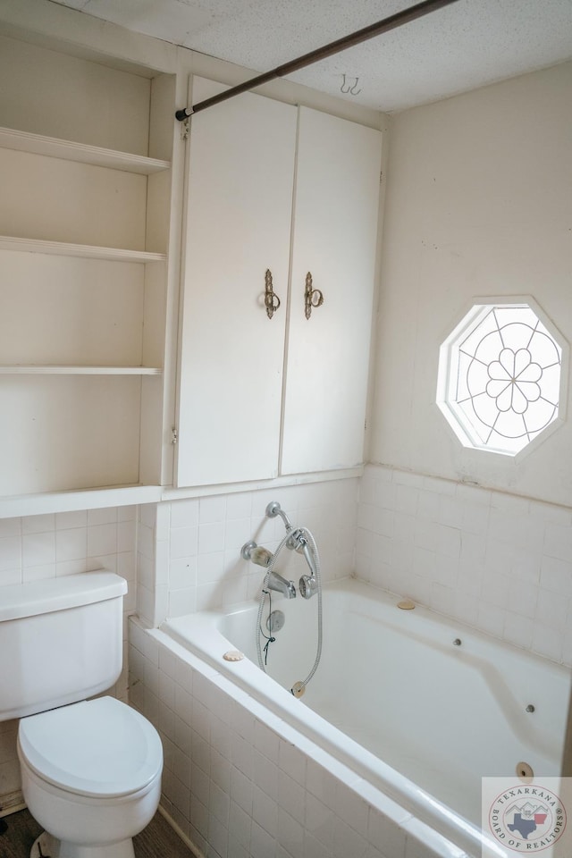 bathroom with toilet and tiled tub