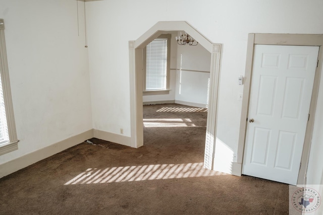 additional living space with a chandelier and dark colored carpet