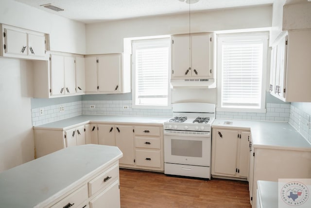 kitchen with decorative backsplash, white gas stove, and light hardwood / wood-style flooring