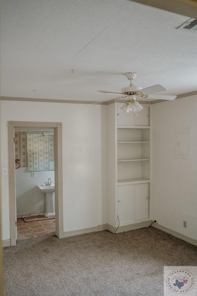 spare room featuring electric panel, ceiling fan, light colored carpet, and a textured ceiling