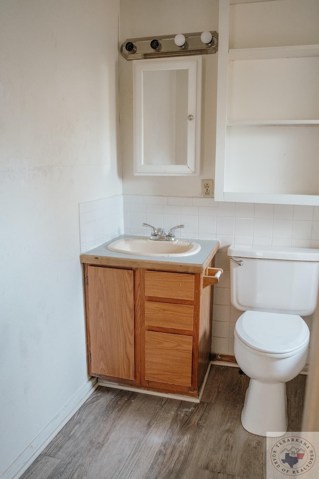 bathroom with wood-type flooring, toilet, vanity, and tile walls