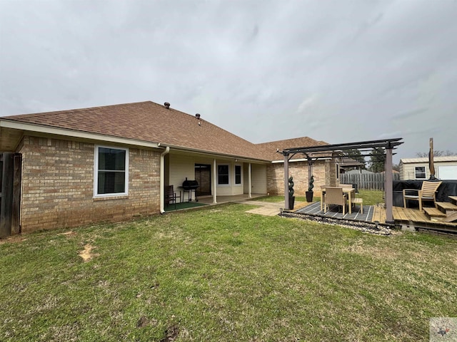 back of house featuring brick siding, a lawn, fence, a deck, and a pergola