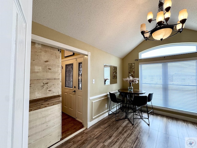 dining space with a chandelier, vaulted ceiling, a textured ceiling, and wood finished floors