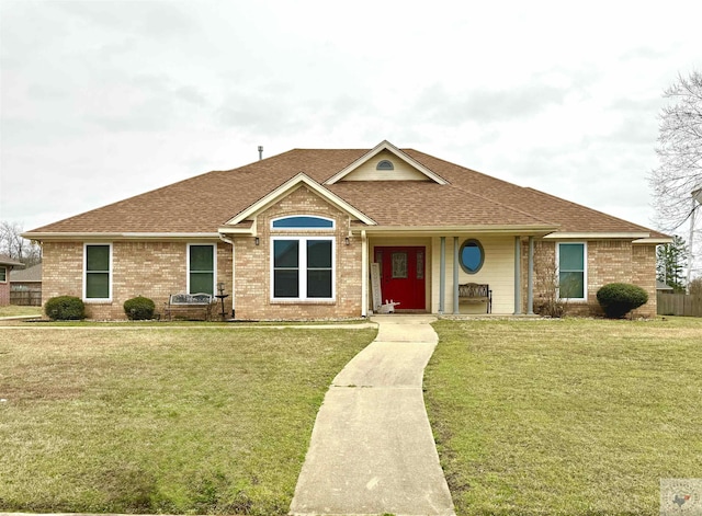 single story home with brick siding, a shingled roof, and a front yard