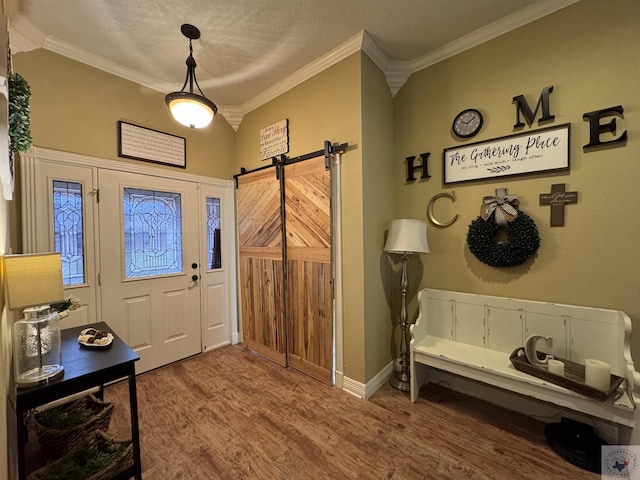 entrance foyer with wood finished floors, crown molding, baseboards, and a barn door