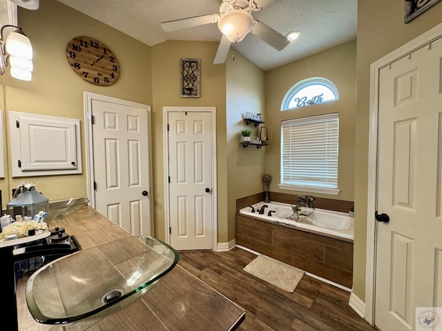 bathroom with baseboards, lofted ceiling, ceiling fan, wood finished floors, and a bath