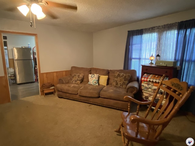 203 Patterson St, Naples, TX 75568 - carpeted living room with wainscoting, a ceiling fan, a textured ceiling, and wooden walls
