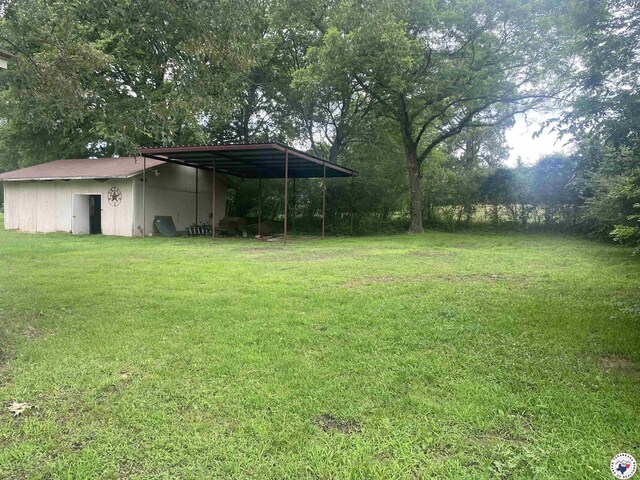 203 Patterson St, Naples, TX 75568 - view of grassy yard featuring a carport and an outbuilding