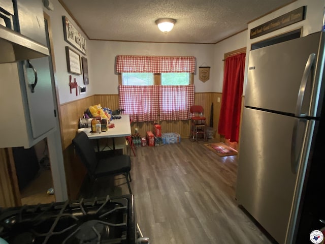 203 Patterson St, Naples, TX 75568 - kitchen featuring freestanding refrigerator, a wainscoted wall, a textured ceiling, wood finished floors, and wooden walls