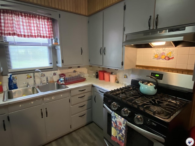 203 Patterson St, Naples, TX 75568 - kitchen with stainless steel gas range, under cabinet range hood, a sink, and backsplash