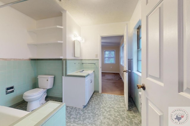 bathroom with vanity, toilet, tile walls, and a textured ceiling