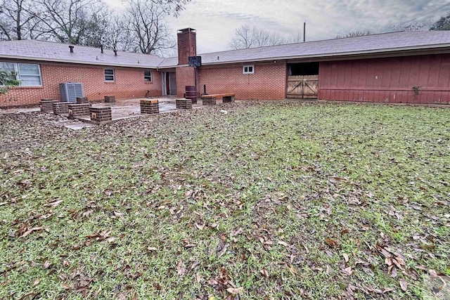 rear view of house with central AC, a yard, and a patio