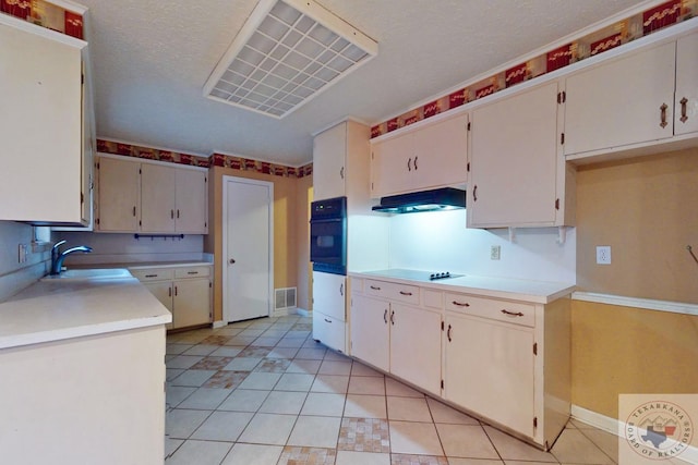 kitchen featuring sink, light tile patterned flooring, black appliances, and a textured ceiling