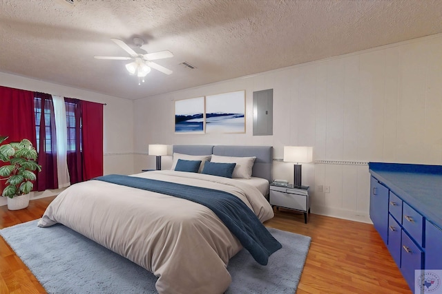 bedroom with ceiling fan, electric panel, a textured ceiling, and wood-type flooring